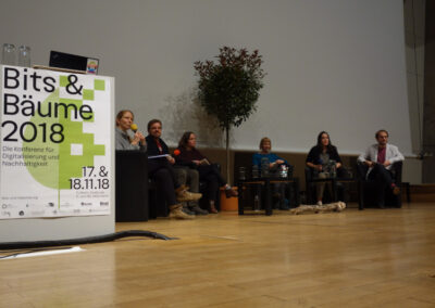 Sechs Menschen sitzen auf einem Podium bei der Konferenz Bits & Bäume