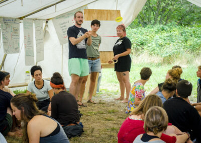 Menschen sitzen und stehen in einem großen Zelt bei einem Workshop der Degwoth-Sommerschule