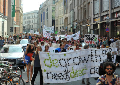 Menschen auf einer Demonstration. Auf dem Banner vorne im Foto steht "degrowth"