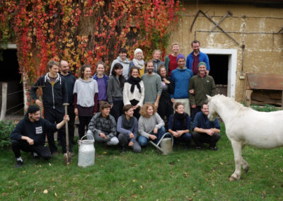 Ein Gruppenfoto der Konzeptwerksmitarbeitenden, die lachend auf einen Esel blicken, der ins Foto läuft