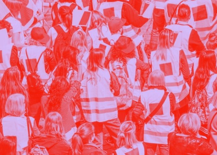 Menschen mit Gewerkschaftswesten bei einer Demonstration von hinten. In pink/rot eingefärbt