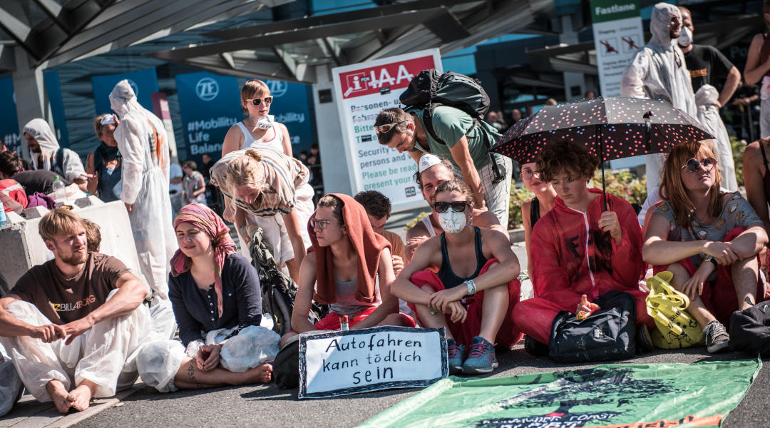 Ein Gruppenfoto von etwa 20 jungen Menschen auf einer Protestaktion mit dem Schild "Autofahren kann tödlich sein"
