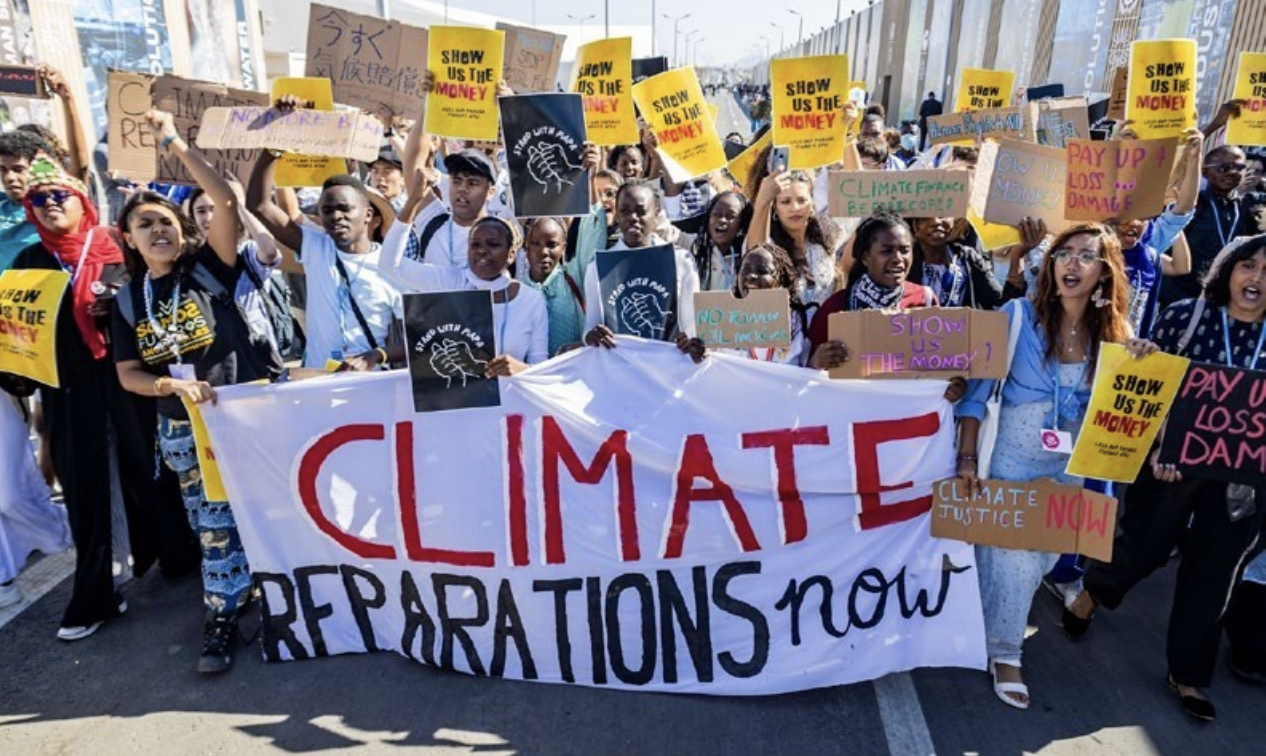 Climatere Reparations Now Banner auf einer Demonstration