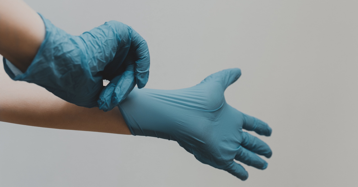 Hände, die sich Latexhandschue überziehen
