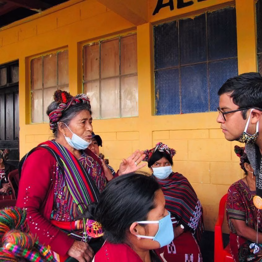 Mehrere Menschen stehen vor einer Hauswand und unterhalten sich.