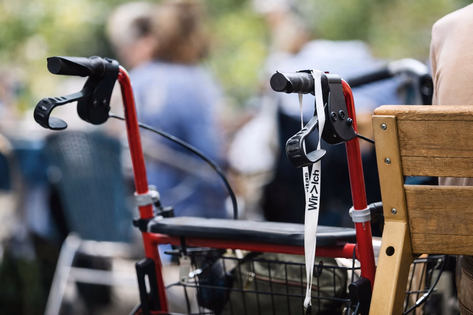 Ein Rollator steht neben einer Parkbank unter freiem Himmel